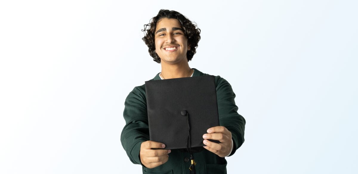 Boy smiling holding a graduation hat