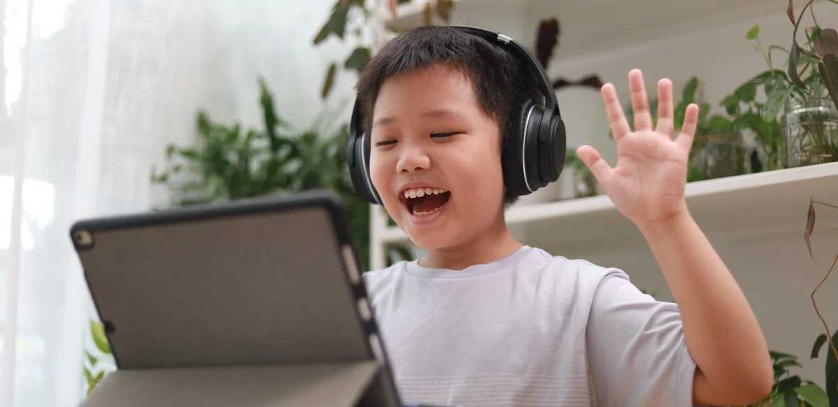 Elementary student attending to an online class wearing a black pair of headphones
