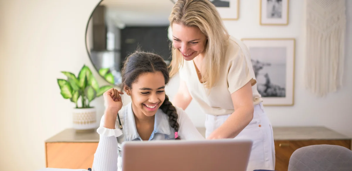Mother and daughter working together on their laptop at home