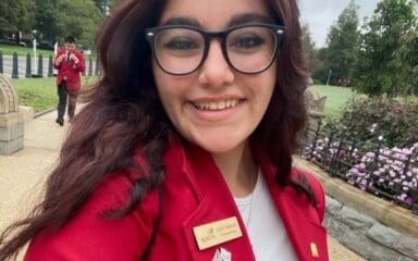 Girl wearing glasses and a red coat taking a selfie